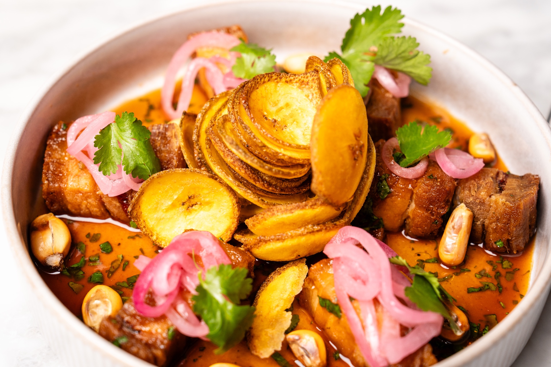 Crispy pork belly with plantain chips and pickled onion