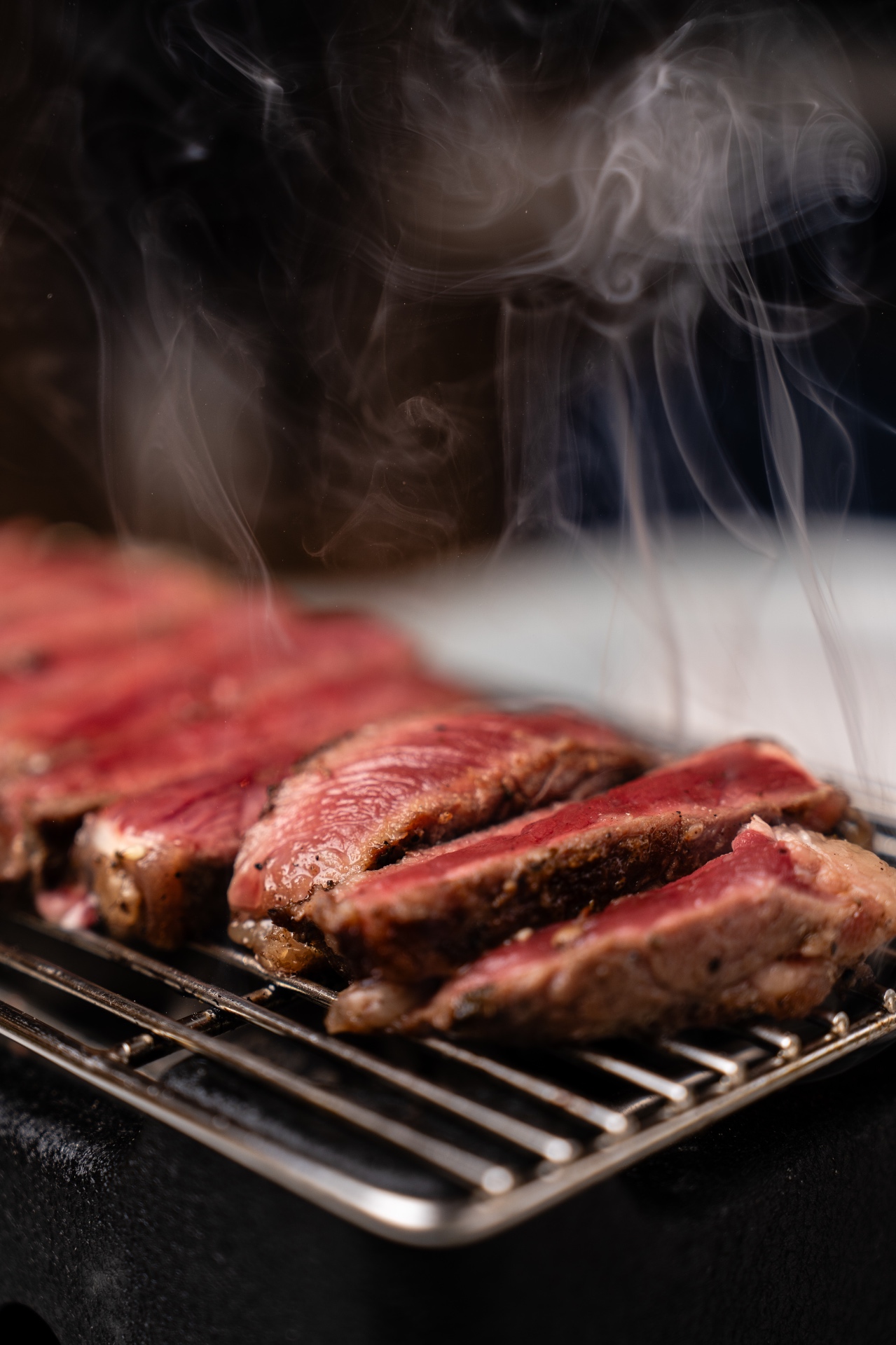Sliced steak resting on the grill with rising steam