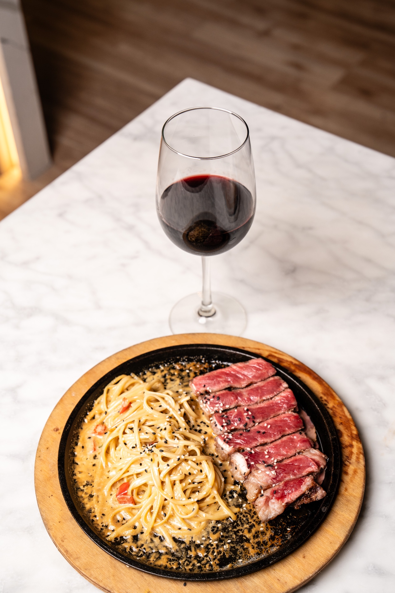 Sliced steak with creamy pasta and a glass of red wine